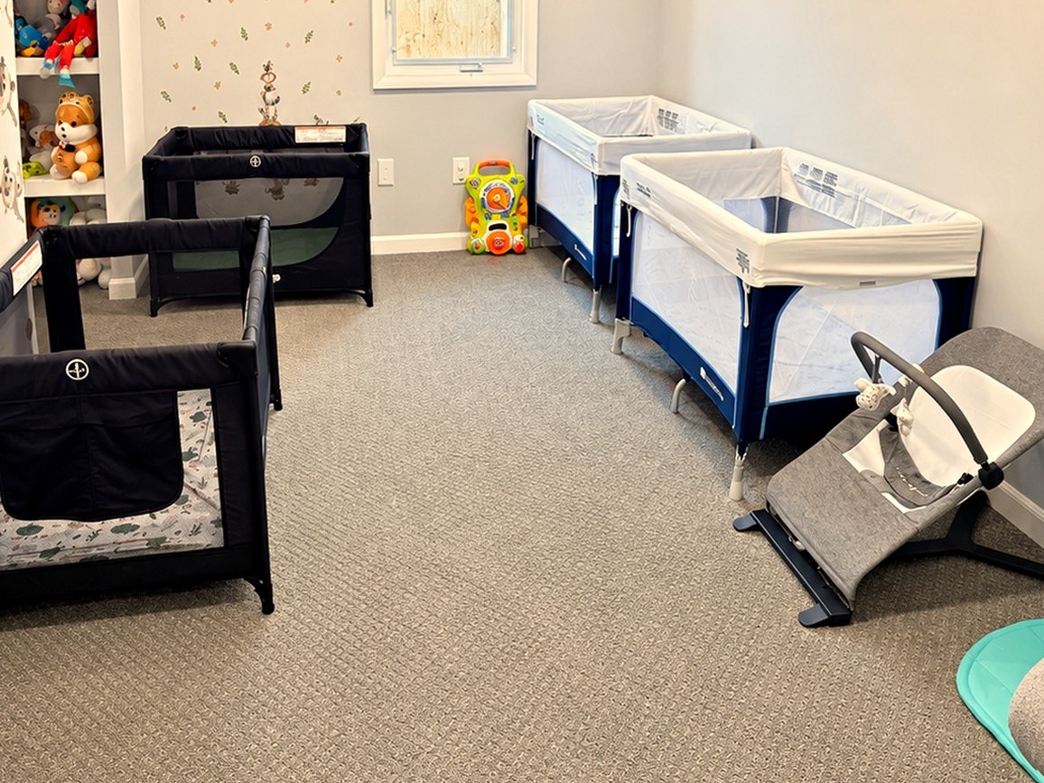 Infant room with portable cribs, a baby bouncer, and soft toys
